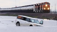 Sebuah kereta melintas saat banjir dari Sungai Tule menggenangi area tersebut setelah hujan lebat berhari-hari di Corcoran, California, AS, 22 Maret 2023.