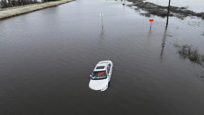 A car sits abandoned on a road as floodwaters from the Tule River inundate the area after days of heavy rain in Corcoran, California, U.S., March 22, 2023. REUTERS/David Swanson