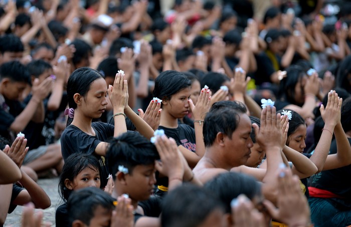 Pemuka agama Hindu memercikkan air suci kepada warga usai mengikuti tradisi Mebuug-Buugan atau mandi lumpur di Desa Kedonganan, Badung, Bali, Kamis (23/3/2023). Tradisi Mebuug-Buugan yang dilakukan setelah Hari Raya Nyepi tersebut dilakukan sebagai simbol menghilangkan kekotoran atau hal-hal negatif. ANTARA FOTO/Fikri Yusuf/YU