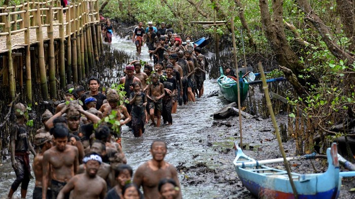 Potret Mebuug-Buugan, Tradisi Mandi Lumpur Usai Nyepi di Bali Pemuka agama Hindu memercikkan air suci kepada warga usai mengikuti tradisi Mebuug-Buugan atau mandi lumpur di Desa Kedonganan, Badung, Bali, Kamis (23/3/2023). Tradisi Mebuug-Buugan yang dilakukan setelah Hari Raya Nyepi tersebut dilakukan sebagai simbol menghilangkan kekotoran atau hal-hal negatif. ANTARA FOTO/Fikri Yusuf/YU
