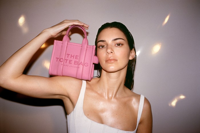 NEW YORK, NEW YORK - FEBRUARY 10: A guest wears a blue faded denim long coat, a navy blue and faded blue embroidered denim yoke Tote Bag handbag from Marc Jacobs, navy blue denim large pants, red shiny leather gloves, red shiny varnished leather platform soles / block heels ankle boots , outside New York Mens Day, during New York Fashion Week, on February 10, 2023 in New York City. (Photo by Edward Berthelot/Getty Images)