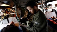 Petugas medis bergerak mondar-mandir di koridor sempit bus medis untuk memberikan perawatan kepada tentara yang terluka.
