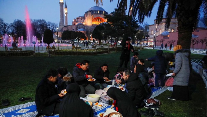 People, with the Ayasofya-i Kebir Camii or Hagia Sophia Grand Mosque in the background, have their iftar (breaking fast) meal at Sultanahmet Square during first day of the holy month of Ramadan in Istanbul, Turkey, March 23, 2023. REUTERS/Dilara Senkaya