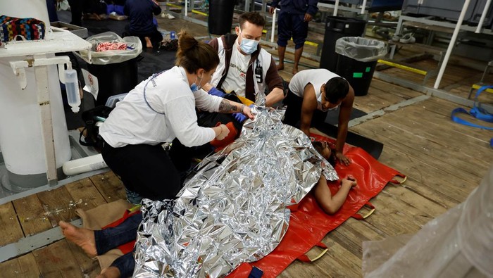 Medics tend to a semi-conscious migrant on the Geo Barents rescue ship, operated by Medecins Sans Frontieres (Doctors Without Borders), after being rescued from a wooden boat off the coast of Libya in the central Mediterranean Sea March 24, 2023. REUTERS/Darrin Zammit Lupi
