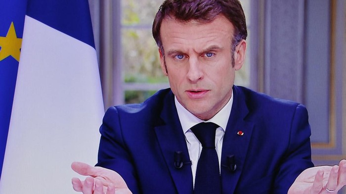 French President Emmanuel Macron is seen on screen as he speaks during a TV interview from the Elysee Palace, in Paris, on March 22, 2023. - French President is to make on March 22, 2023 his first public comments on the crisis sparked by his government forcing through a pensions overhaul, which has sparked violent protests and questions over his ability to bring about further change. (Photo by Ludovic MARIN / AFP)