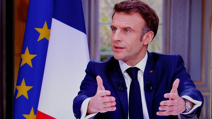 French President Emmanuel Macron is seen on screen as he speaks during a TV interview from the Elysee Palace, in Paris, on March 22, 2023. - French President is to make on March 22, 2023 his first public comments on the crisis sparked by his government forcing through a pensions overhaul, which has sparked violent protests and questions over his ability to bring about further change. (Photo by Ludovic MARIN / AFP)