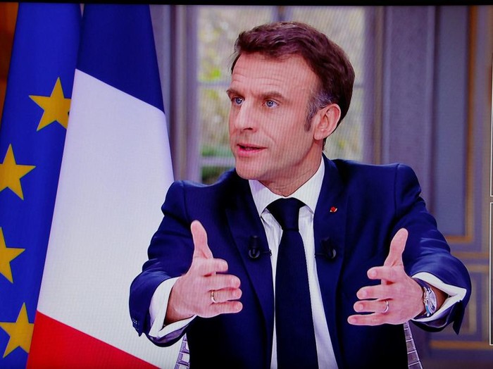 French President Emmanuel Macron is seen on screen as he speaks during a TV interview from the Elysee Palace, in Paris, on March 22, 2023. - French President is to make on March 22, 2023 his first public comments on the crisis sparked by his government forcing through a pensions overhaul, which has sparked violent protests and questions over his ability to bring about further change. (Photo by Ludovic MARIN / AFP)