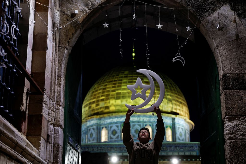 A Palestinian man hangs decorations at an entrance to the compound known to Muslims as the Noble Sanctuary and to Jews as the Temple Mount, ahead of the holy fasting month of Ramadan in Jerusalem's Old City March 20, 2023. REUTERS/Ammar Awad