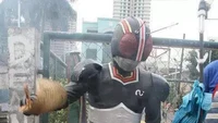 Tampil nyentrik, seorang pedagang sate nekat menggunakan kostum pahlawan demi menarik perhatian. Aksinya memanggang sate terbukti memancing para pelanggan untuk berdatangan. Foto: 1cak.com