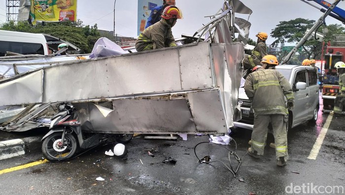 Petugas tengah mengevakuasi reklame yang roboh timpa mobil dan motor di Bandung.