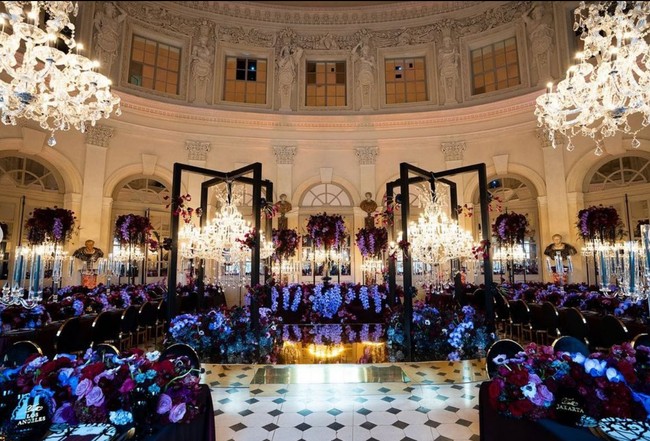 Mengintip suasana resepsi pernikahan, dekorasinya pun dibuat megah dengan nuansa dreamy bak negeri dongeng. Terdapat rangkaian bunga bernuansa ungu di setiap meja yang diduduki para tamu.  Foto: Instagram/@morden.co, @audreyparisphoto