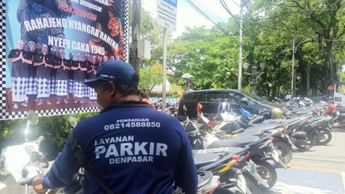 Salah satu petugas parkir di Pura Agung Jagatnatha Denpasar menggunakan seragam yang berisikan nomor telepon pengaduan, Sabtu (25/3/2033).