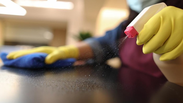Woman wearing yellow gloves cleaning black countertop