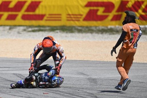 Honda Spanish rider Marc Marquez (TOP) checks on Aprilia Portuguese rider Miguel Oliveira after crashing during the MotoGP race of the Portuguese Grand Prix at the Algarve International Circuit in Portimao, on March 26, 2023. (Photo by PATRICIA DE MELO MOREIRA / AFP)