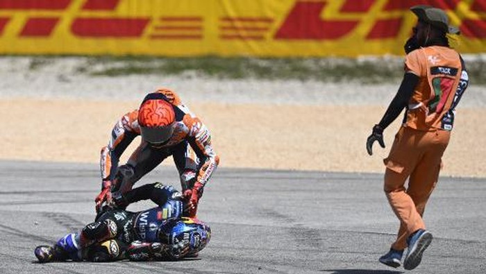 Honda Spanish rider Marc Marquez (TOP) checks on Aprilia Portuguese rider Miguel Oliveira after crashing during the MotoGP race of the Portuguese Grand Prix at the Algarve International Circuit in Portimao, on March 26, 2023. (Photo by PATRICIA DE MELO MOREIRA / AFP)