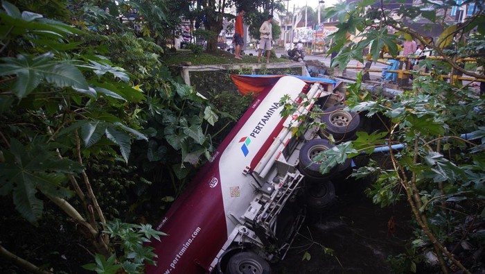 Warga mengamati kondisi truk tangki BBM ber nopol N 9359 UA yang terperosok ke sungai di Desa Bululawang, Malang, Jawa Timur, Minggu (26/3/2023). Kecelakaan tunggal truk tangki yang terjadi sekitar pukul 01.50 WIB tersebut diduga akibat manuver sopir untuk menghindari kendaraan yang tiba-tiba muncul dan menyebabkan satu orang mengalami luka-luka. ANTARA FOTO/Irfan Sumanjaya/Zk/hp.