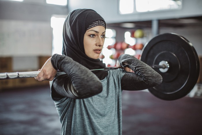 Young woman on cross training weightlifting. Wearing sports clothing and hijab.