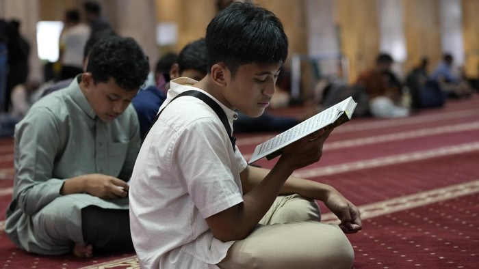 Berlomba-lomba Menimba Pahala di Bulan Puasa Muslim man reads the Quran after first Friday prayer of the fasting month of Ramadan at Istiqlal Mosque in Jakarta, Indonesia, Friday, March 24, 2023. During Ramadan, observant Muslims abstain from food and water from dawn to dusk, before gathering with family and friends for indulgent nighttime meals. According to Islam, fasting draws the faithful closer to God and reminds them of the suffering of the poor. (AP Photo/Achmad Ibrahim)