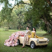 Pemotretan di taman atau hutan kota akan lebih unik dan menarik apabila kamu mengenakan sesuatu yang kontras. Misalnya saja mengenakan busana kuning dan properti mobil berwarna senada dengan latar belakang rumput serta pepohonan hijau. Foto: Weddingku/Danieliben Photography
