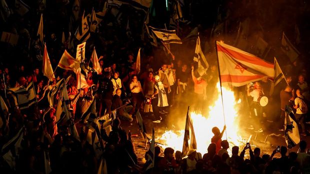 Fire burns as people attend a demonstration after Israeli Prime Minister Benjamin Netanyahu dismissed the defense minister and his nationalist coalition government presses on with its judicial overhaul, in Tel Aviv, Israel, March 27, 2023. REUTERS/Nir Elias
