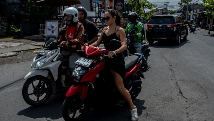 CANGGU, BALI, INDONESIA - MARCH 26: A foreigner tourist rides a motorcycle without helmet at a main road on March 26, 2023 in Canggu, Bali, Indonesia. Indonesian island of the gods plans to enact some rules for foreign tourists on operating motorcycles, scooters, and cars for travel around the island following a number of violations of traffic rules and bad behavior such as riding motorcycles without valid paperwork and helmets, driving recklessly, using fake Indonesian ID cards or abusing residence and work permits. (Photo by Agunng Parameswara/Getty Images)