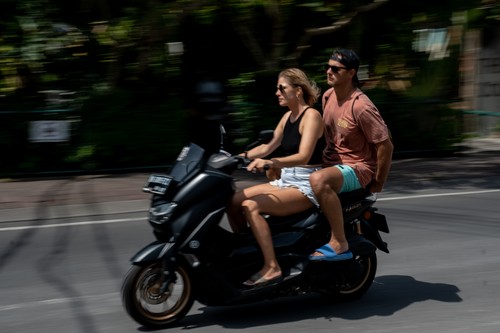 CANGGU, BALI, INDONESIA - MARCH 26: A foreigner tourist rides a motorcycle without helmet at a main road on March 26, 2023 in Canggu, Bali, Indonesia. Indonesian island of the gods plans to enact some rules for foreign tourists on operating motorcycles, scooters, and cars for travel around the island following a number of violations of traffic rules and bad behavior such as riding motorcycles without valid paperwork and helmets, driving recklessly, using fake Indonesian ID cards or abusing residence and work permits. (Photo by Agunng Parameswara/Getty Images)