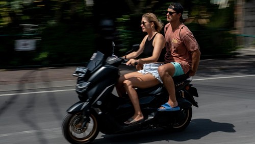 CANGGU, BALI, INDONESIA - MARCH 26: A foreigner tourist rides a motorcycle without helmet at a main road on March 26, 2023 in Canggu, Bali, Indonesia. Indonesian island of the gods plans to enact some rules for foreign tourists on operating motorcycles, scooters, and cars for travel around the island following a number of violations of traffic rules and bad behavior such as riding motorcycles without valid paperwork and helmets, driving recklessly, using fake Indonesian ID cards or abusing residence and work permits. (Photo by Agunng Parameswara/Getty Images)