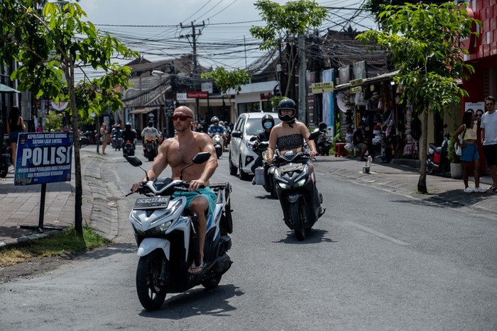 CANGGU, BALI, INDONESIA - MARCH 26: A foreigner tourist rides a motorcycle without helmet at a main road on March 26, 2023 in Canggu, Bali, Indonesia. Indonesian island of the gods plans to enact some rules for foreign tourists on operating motorcycles, scooters, and cars for travel around the island following a number of violations of traffic rules and bad behavior such as riding motorcycles without valid paperwork and helmets, driving recklessly, using fake Indonesian ID cards or abusing residence and work permits. (Photo by Agunng Parameswara/Getty Images)