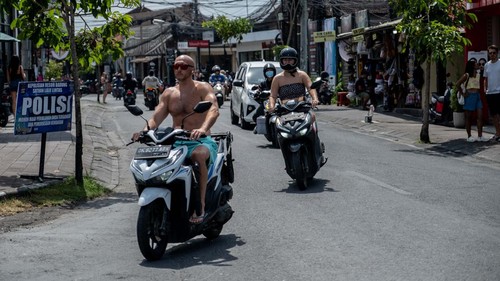 CANGGU, BALI, INDONESIA - MARCH 26: A foreigner tourist rides a motorcycle without helmet at a main road on March 26, 2023 in Canggu, Bali, Indonesia. Indonesian island of the gods plans to enact some rules for foreign tourists on operating motorcycles, scooters, and cars for travel around the island following a number of violations of traffic rules and bad behavior such as riding motorcycles without valid paperwork and helmets, driving recklessly, using fake Indonesian ID cards or abusing residence and work permits. (Photo by Agunng Parameswara/Getty Images)