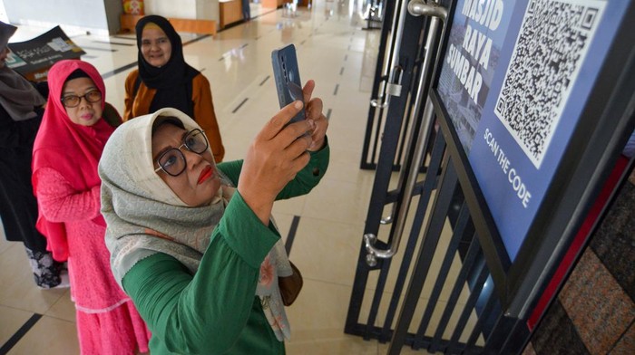 Pengunjung memindai QR code untuk mengisi buku tamu di Masjid Raya Sumatera Barat di Padang, Senin (27/3/2023). Masjid Raya Sumatera Barat bekerja sama dengan Dinas Komunikasi Informatika dan Statistik (Diskominfotik) Sumbar dalam melakukan digitalisasi terhadap pelayanan di masjid tersebut, di antaranya pengisian buku tamu, survei, pembayaran infak dan informasi masjid melalui QR Code serta pelayanan wifi gratis bagi pengunjung.