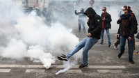 Massa aksi menendang tabung gas air mata di tengah bentrokan dengan polisi di Paris, Prancis. Reuters/Yves Herman.