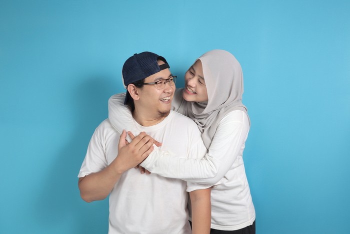 Portrait of happy Asian muslim couple smiling, husband and wife hugging full of love, family concept