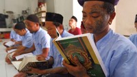 Salah satu napi yang mengenakan tato di wajah hingga tangannya ini, membaca Al-Quran dengan khidmat.