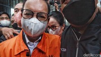 Tampak Ary Egahni berusaha sembunyi di belakang punggung suaminya dan menghindari kamera wartawan saat keluar gedung dan masuk ke mobil tahanan. 