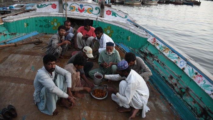 Kebersamaan Nelayan Pakistan Saat Buka Puasa di Atas Kapal KARACHI, PAKISTAN - MARCH 27: Pakistani fishermen break their Ramadan fast (iftar) on their boats during the Muslim holy fasting month of Ramadan in Karachi, Pakistan, on March 27, 2023. (Photo by Sabir Mazhar/Anadolu Agency via Getty Images)