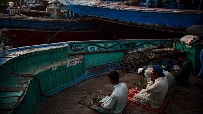 Kebersamaan Nelayan Pakistan Saat Buka Puasa di Atas Kapal KARACHI, PAKISTAN - MARCH 27: Pakistani fishermen break their Ramadan fast (iftar) on their boats during the Muslim holy fasting month of Ramadan in Karachi, Pakistan, on March 27, 2023. (Photo by Sabir Mazhar/Anadolu Agency via Getty Images)