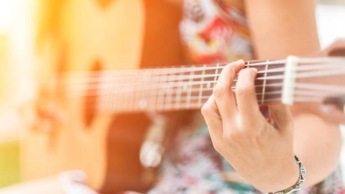 Woman playing acoustic guitar outdoors
