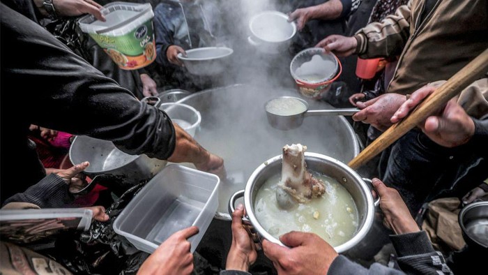 Potret Berbagi Sup Gratis untuk Warga Gaza TOPSHOT - Palestinian Walid al-Hattab (top R) hands out soup from a large pot to impoverished youths to break their fast on the second day of the Muslim holy month of Ramadan in Gaza City on March 24, 2023. (Photo by MOHAMMED ABED / AFP) (Photo by MOHAMMED ABED/AFP via Getty Images)