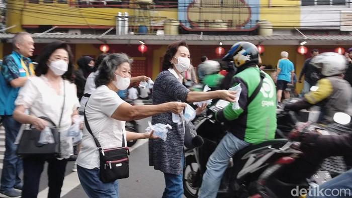 Sejumlah warga yang berasal dari komunitas Tionghoa bersama polisi membagikan takjil buka puasa kepada para pengendara jalan tepatnya di depan Masjid Lautze 2, Selasa (28/3/2023).