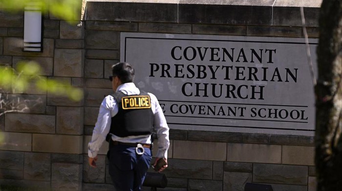 A police officer walks by an entrance to The Covenant School after a shooting in Nashville, Tenn. on Monday, March 27, 2023. (AP Photo/John Amis)