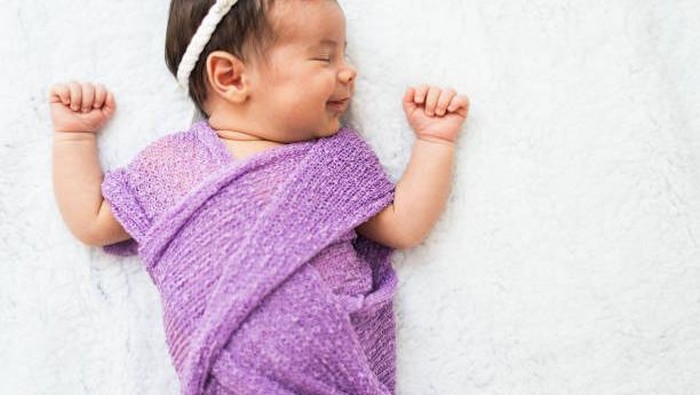 Close-up of a newborn baby girl peacefully sleeping in the crib. High angle view.
