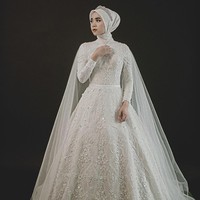 Gaun model ballgown dengan taburan payet, kristal serta bordir membuat tampilan berkesan megah dan cantik. Ditambah cape transparan berbahan sifon yang menambah kesan dramatis. Cocok untuk pernikahan di ballroom atau ruangan berukuran besar. Foto: Weddingku/ Ivory Bridal