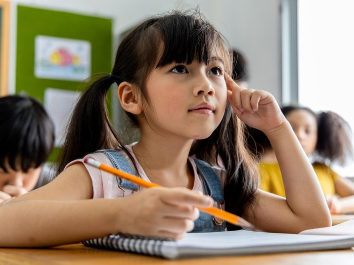 Portrait of an Asian child girl student thinking and solving the subject matter studied in the classroom. School education concept