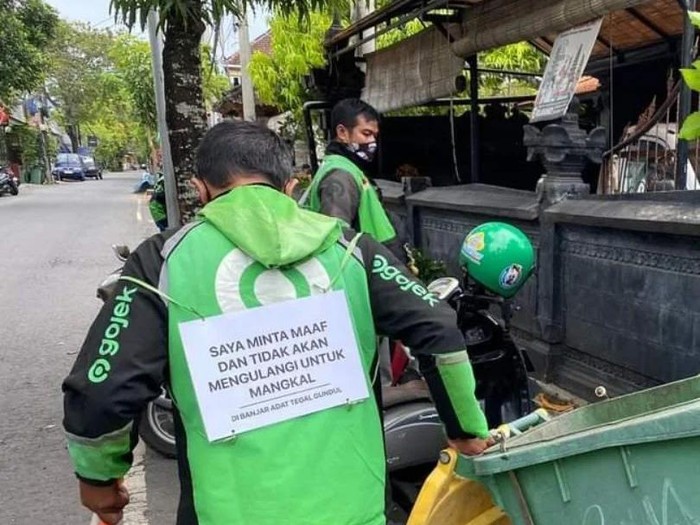 Belasan pengemudi ojek online menyapu di pinggir jalan, sebagai sanksi mangkal di sembarang tempat di Canggu, Badung.