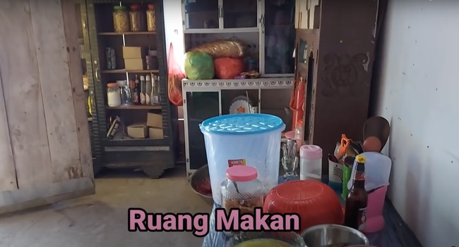 Di bagian dalam rumah terdapat ruang makan yang juga sederhana. Ruang makan tersebut tampak dipenuhi dengan barang-barang dan makanan. Foto: YouTube/Daily Indah