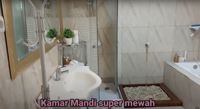 Di dalam kamar juga terdapat kamar mandi yang tak kalah mewah. Bahkan kamar mandinya itu dilengkapi dengan bathtub dan kaca cukup besar yang dipasang di atas wastafel. Foto: YouTube/Daily Indah