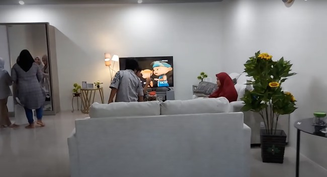 Di sebelah tempat tidurnya terdapat tempat untuk bersantai dan menonton televisi. Dilengkapi dengan sofa besar berwarna putih dan sebuah televisi, fasilitas kamar tersebut terlihat cukup mewah. Foto: YouTube/Daily Indah