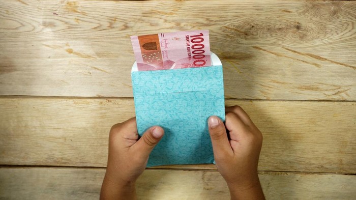 Hand of young kid holding indonesian money. Rupiah/IDR money.
