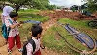 Anak-anak sekolah melihat proses pengerukan embung.