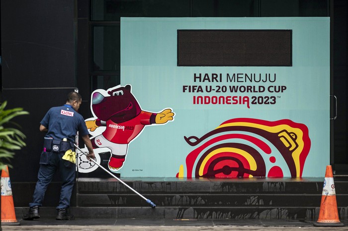 Warga berjalan di dekat papan promosi Piala Dunia U-20 Indonesia 2023 di kawasan GBK Arena, Jakarta, Kamis (30/3/2023). FIFA resmi mencabut status Indonesia sebagai tuan rumah untuk gelaran Piala Dunia U-20 2023 mendatang.